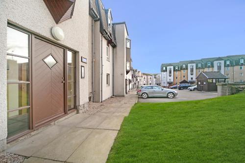 a car parked in a parking lot next to a building at Strawberry Bank Apartment ✪ Grampian Lettings Ltd in Aberdeen