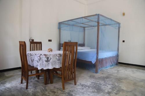 a bedroom with a table and a canopy bed at Raviya Place in Dickwella