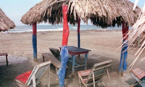 una mesa y sillas bajo una sombrilla de paja en la playa en HERMOSA CASA PLAYERA CON MESA DE BILLAR, en Juan de Acosta