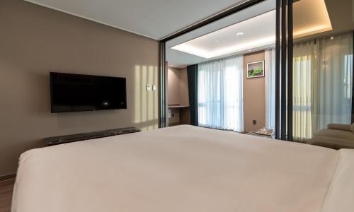 a bedroom with a large white bed and a flat screen tv at D OV Haeundae Hotel in Busan