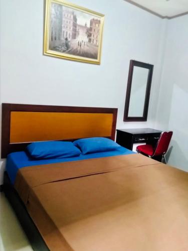 een slaapkamer met een bed met een houten hoofdeinde en een spiegel bij TW penginapan in Cianjur