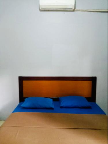 een bed met een houten hoofdeinde en blauwe kussens bij TW penginapan in Cianjur