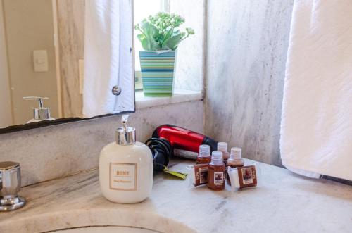 a bathroom sink with bottles of soap and a mirror at Pousada do Lago 2 in Petrópolis