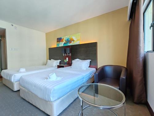 a hotel room with two beds and a glass table at Greenage MingSuite 明绿时代套房 Kota Kinabalu 亚庇市中心 in Kota Kinabalu