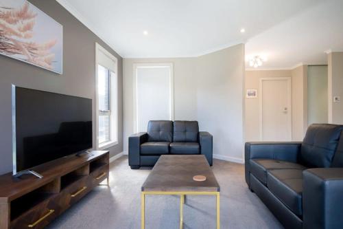a living room with two blue couches and a tv at Cute and Cosy 2 Bedroom Unit with Parking and WiFi in Kings Meadows