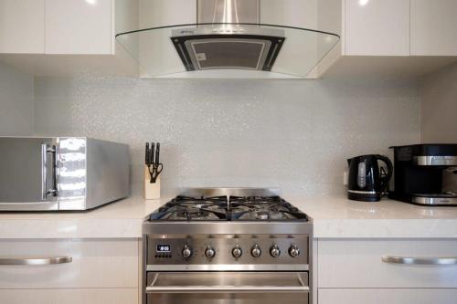 a stove top oven in a kitchen with a microwave at Cute and Cosy 2 Bedroom Unit with Parking and WiFi in Kings Meadows