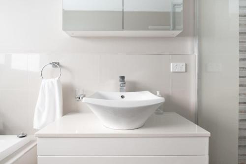 a white bathroom with a sink and a mirror at Cute and Cosy 2 Bedroom Unit with Parking and WiFi in Kings Meadows