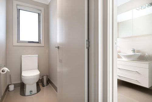a white bathroom with a toilet and a sink at Cute and Cosy 2 Bedroom Unit with Parking and WiFi in Kings Meadows