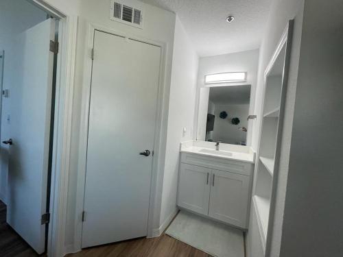 a white bathroom with a sink and a mirror at Great Apt Close Disney Spring in Orlando