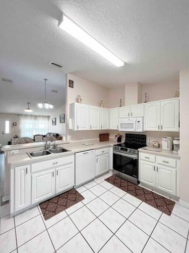 a kitchen with white cabinets and a sink and stove at Tranquility Home near Beaches in Palm Coast