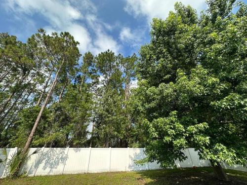 a fence with trees in front of a field at Tranquility Home near Beaches in Palm Coast