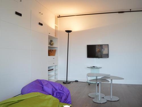 une pièce avec une table et une télévision sur un mur dans l'établissement Appartement moderne 4 pers avec vue mer, parking, lave-vaisselle et lave-linge - FR-1-225C-137, à Banyuls-sur-Mer