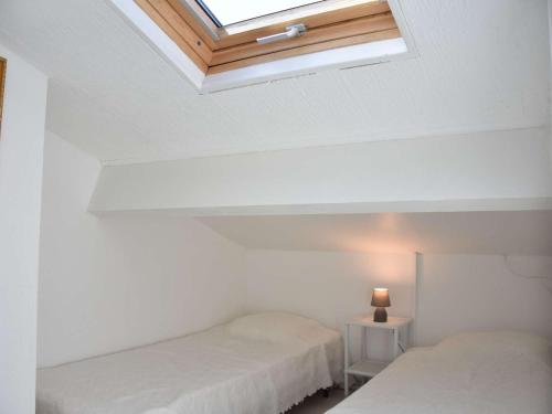 une chambre blanche avec deux lits et une lucarne dans l'établissement Maison familiale climatisée 4 pièces, 6 couchages, à 100m de la plage - Gruissan Les Ayguades - FR-1-229-878, à Gruissan