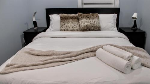 - un lit avec des draps blancs et des serviettes dans l'établissement Chalet Labonté, à Mont-Tremblant