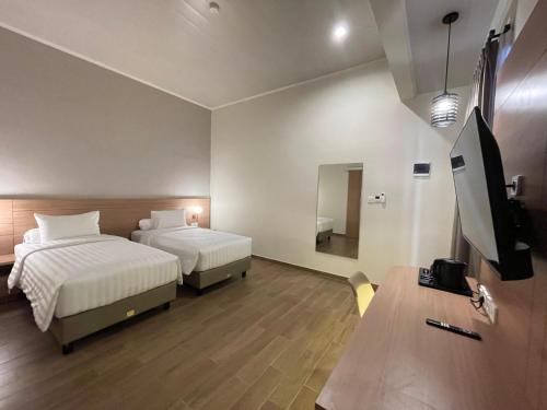 a hotel room with two beds and a flat screen tv at Azana Essence Sanggabuana Bogor in Kamparganya
