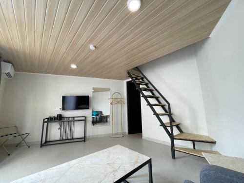 a living room with a spiral staircase and a television at Azana Essence Sanggabuana Bogor in Kamparganya