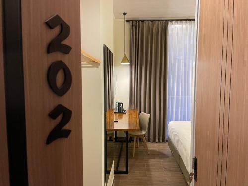 a hotel room with a bed and a table with a desk at Azana Essence Sanggabuana Bogor in Kamparganya