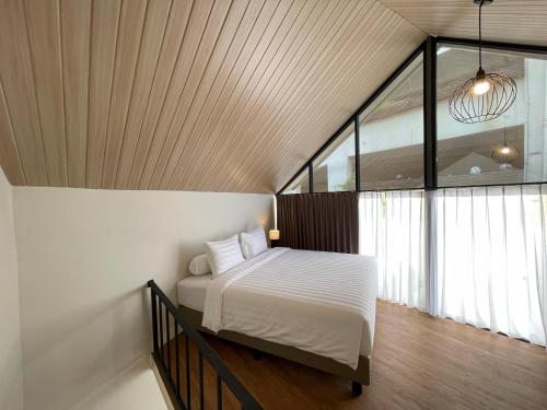 a bedroom with a bed and a large window at Azana Essence Sanggabuana Bogor in Kamparganya