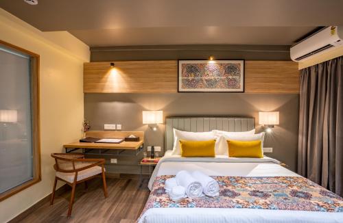 a hotel room with a bed and a desk and a window at Regenta Central Puri Odisha in Puri