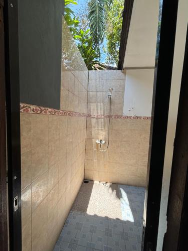 e bagno piastrellato con doccia e finestra. di Bahari Beach Amed ad Amed