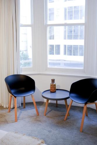 two chairs and a table in a room with a window at #55highstreetauckland in Auckland