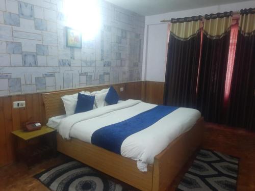 um quarto com uma cama com lençóis azuis e brancos em Indraprastha Cottage em Dharmsala