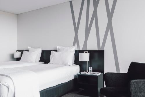 a bedroom with a large bed and a chair at Quay West Suites Melbourne in Melbourne