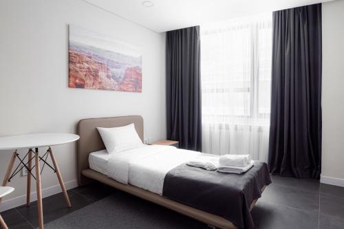 um quarto com uma cama, uma mesa e uma janela em HIGHVIL APARTAMENTS em Astana