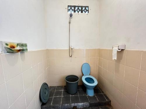 a bathroom with a blue toilet and a trash can at Alan's Homestay in Kuripan