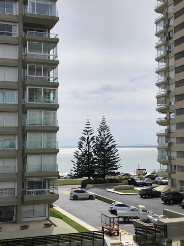 a parking lot in front of a building with cars at Hotel Gaudí in Punta del Este