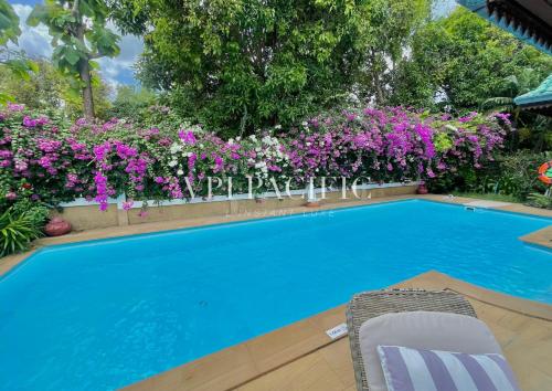 a swimming pool with purple flowers and a chair next to it at Alicia Pool Villa Samui in Mae Nam