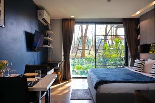 une chambre avec un lit, un bureau et une fenêtre dans l'établissement Luxury Modern Garden View Apartment, à Chiang Mai
