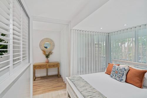 a white bedroom with a bed and a window at Belle Escapes Drift Beachfront Resort Suite 4403 in Palm Cove