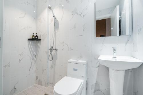 a white bathroom with a toilet and a sink at Joy Hongqiao Airport and Railway Hotel in Shanghai