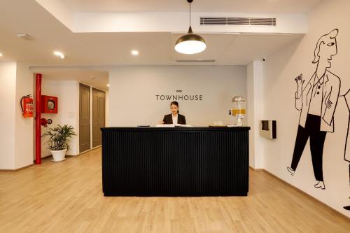 Un hombre sentado en un mostrador de recepción en una habitación. en Townhouse Golden Avenue Road, en Amritsar