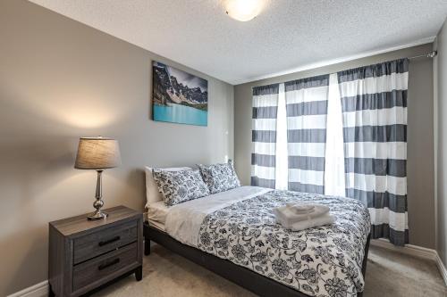 a bedroom with a bed with a nightstand and a window at Lux-Rooms in Allard Edmonton in Edmonton