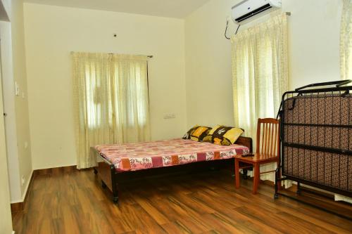 een slaapkamer met een bed en een stoel in een kamer bij Narayani Resort - Serene resort with private swimming pool in Tiruvannamalai