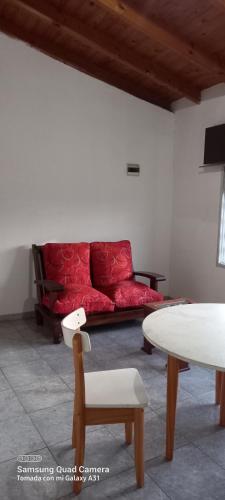 um sofá vermelho num quarto com uma mesa e cadeiras em La posada del viento em Villa El Rincón
