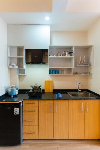 a kitchen with wooden cabinets and a black refrigerator at POKHARA APARTMENTS INN in Pokhara