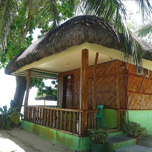a small house with a straw roof and a chair at Coolis beach in Masbate