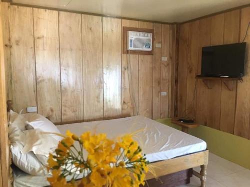 a bedroom with a bed with a vase of yellow flowers at Coolis beach in Masbate