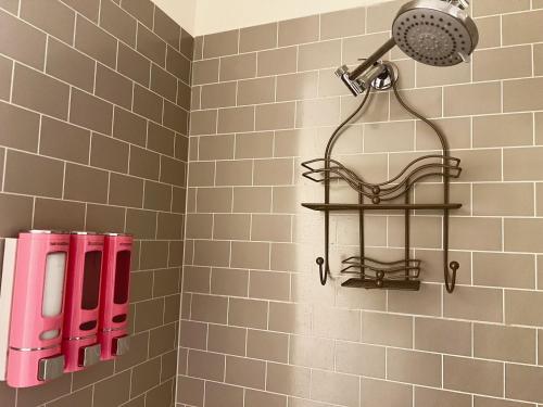a bathroom with a shower with pink bottles on the wall at LittleBettysCrashPad in Torrance