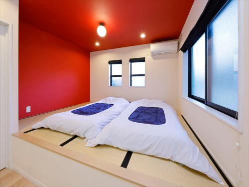東京にあるCOTO東京 渋谷3の赤い壁のドミトリールーム ベッド2台