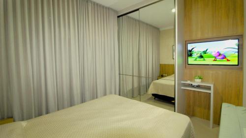 Habitación de hotel con TV y cama en 1072 - Apartamento 3 suítes Alto Padrão com SPA na Praia de Bombinhas, en Bombinhas