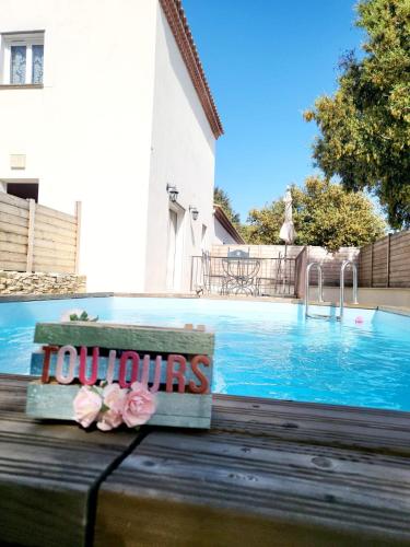 un banc avec des fleurs roses assis à côté d'une piscine dans l'établissement Villa Maélie, à Uzès