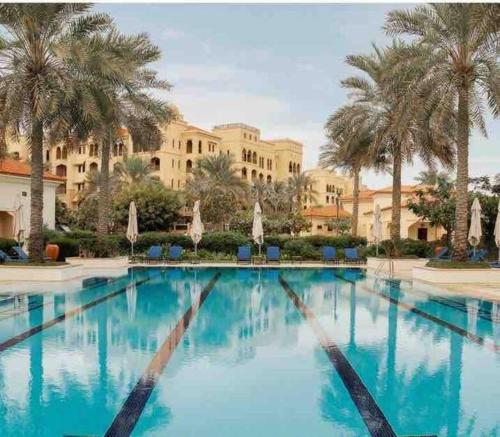 a large swimming pool with palm trees and a building at Three bedroom apartment in Saadiyat district in Abu Dhabi