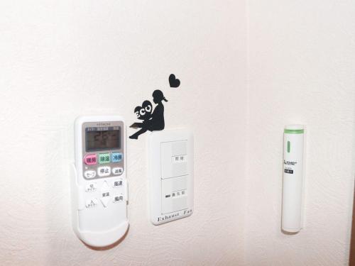 a wall with a cell phone and a remote control at ＧＵＥＳＴ　ＨＯＵＳＥ　てぃんが〜ら in Sobe