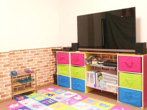 a living room with a tv and colorful drawers at ＧＵＥＳＴ　ＨＯＵＳＥ　てぃんが〜ら in Sobe