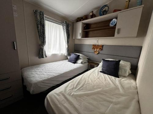 mały pokój z 2 łóżkami i oknem w obiekcie Beautiful Caravan With Decking At Azure Seas Ref 32060az w mieście Lowestoft