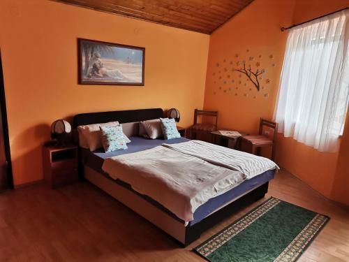 a bedroom with a bed with orange walls at Fenyő Vendégház in Parádsasvár